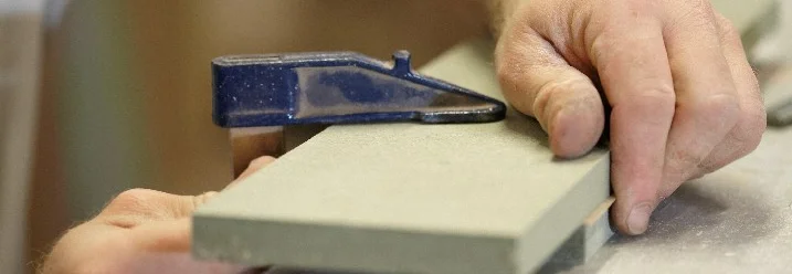 Person fixiert Holzleiste mit Zwinge.